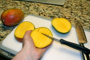 Cut your mango by first slicing off one side and then the other as close to the pit as you can. Then use a knife to cut each side of the mango into squares (not cutting through the skin). Then use a spoon to scoop the mango out.